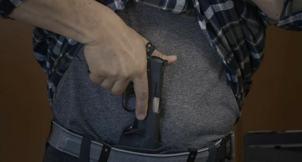 a man holstering a sa-35 compact 4 inch barrel pistol